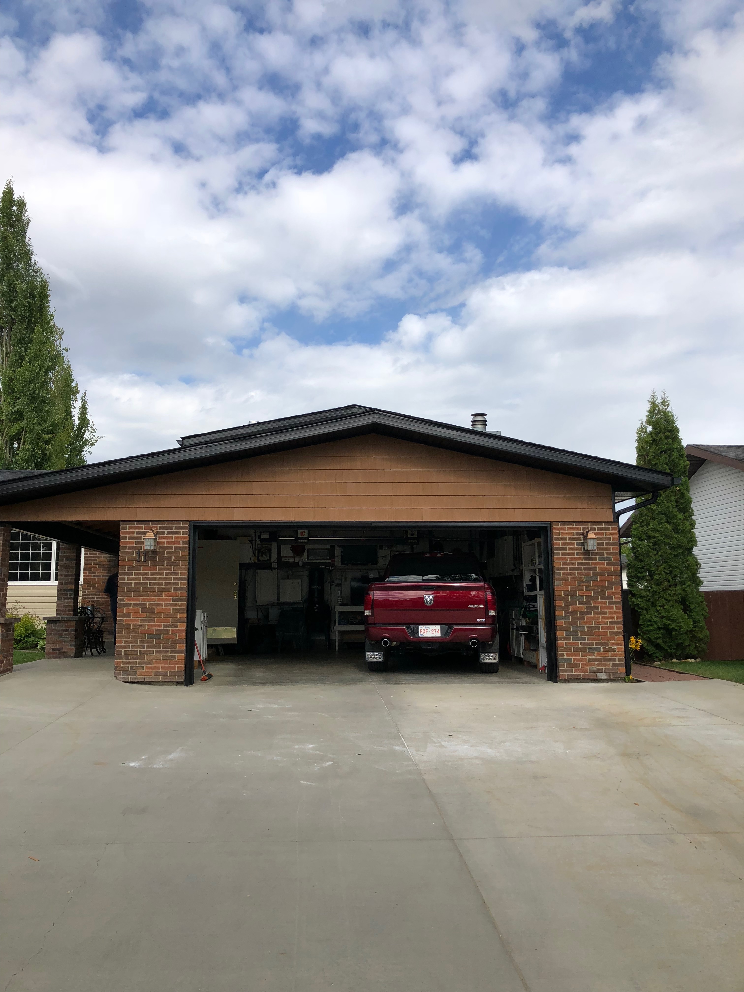 Brick garage with an open door showing a red pickup truck and overcast sky above.
